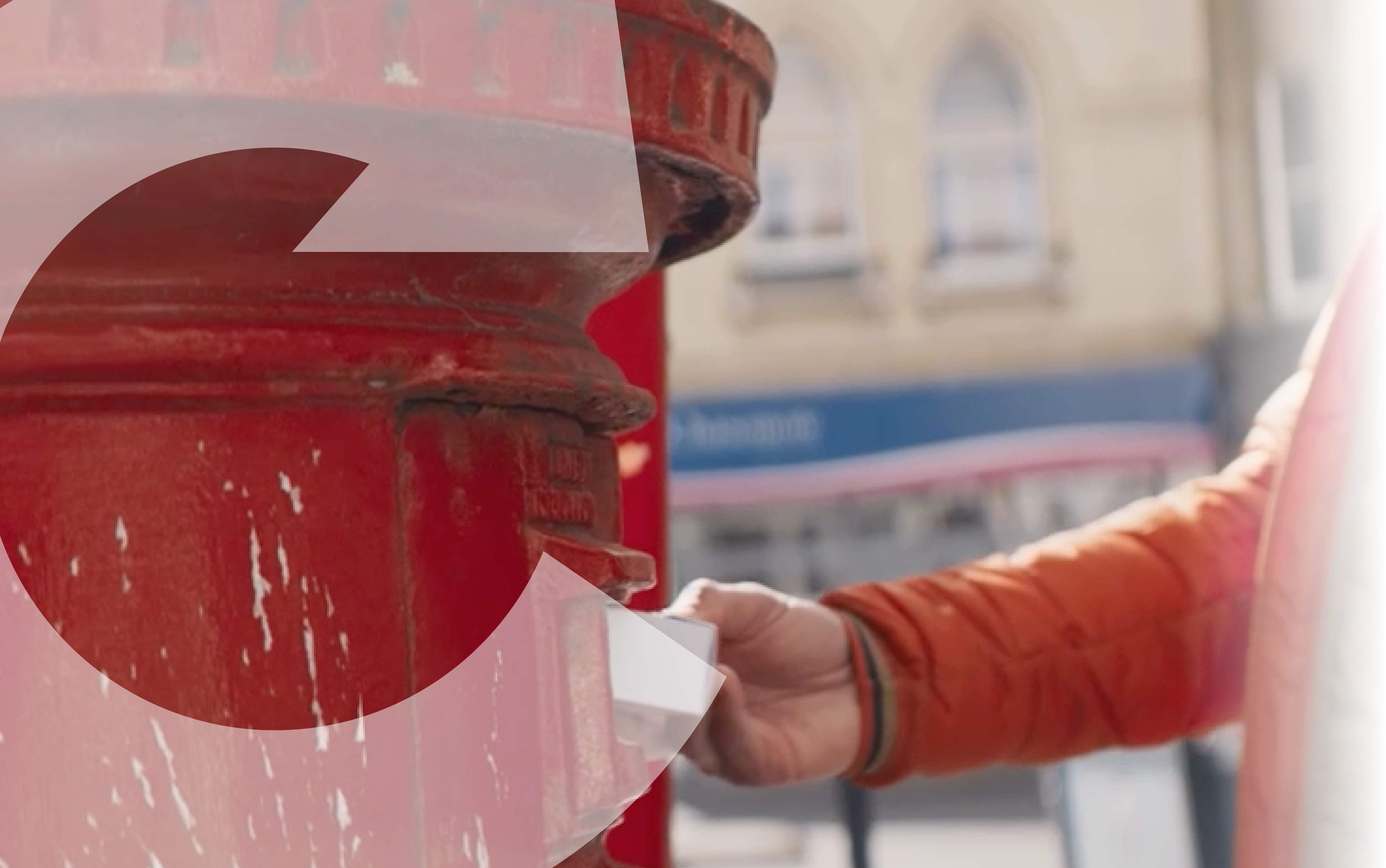 A person placing a white box into a red post box.