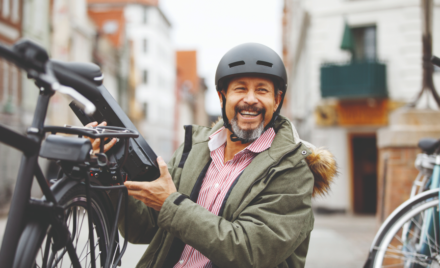 Man smiling carrying a bicycle