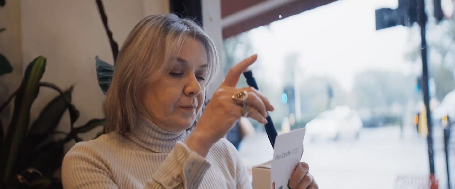 Close-up of a person inserting a Novo Nordisk pen and into a PenCycle box near a window.