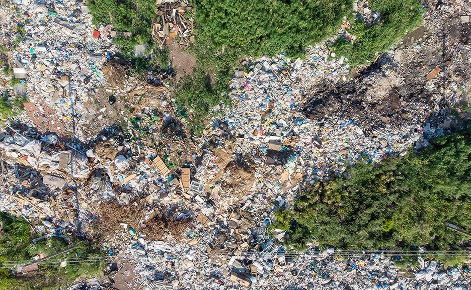 Land contamination with plastic bottles and bags. Open storage of solid waste garbage. Aerial top view.